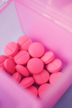close up of pink color medical pills in a pill box on table