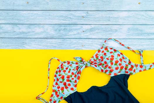 Top view of the swimsuit lying on a blue wooden and yellow background.Summer vacation concept