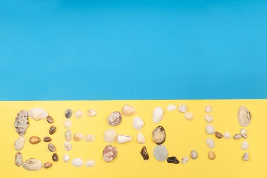 The inscription of the word beach is made of shells on a yellow-blue background.Travel concept