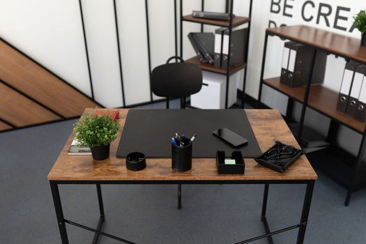 office desk in an empty office with office supplies and a leather pad