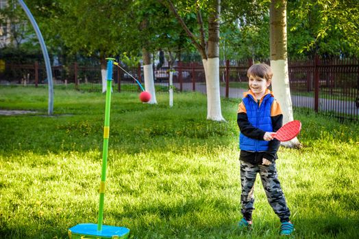 Happy boy is playing tetherball swing ball game in summer camping. Happy leisure healthy active time outdoors concept