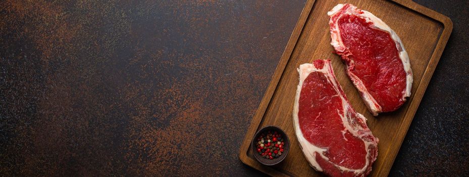 Two raw meat beef rib eye marbled steaks on wooden cutting board