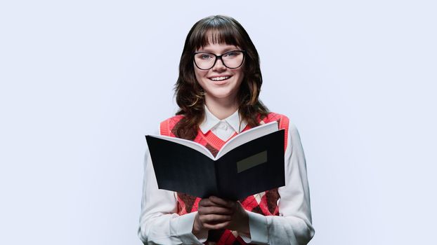 College university student reading exercise book, on light studio background