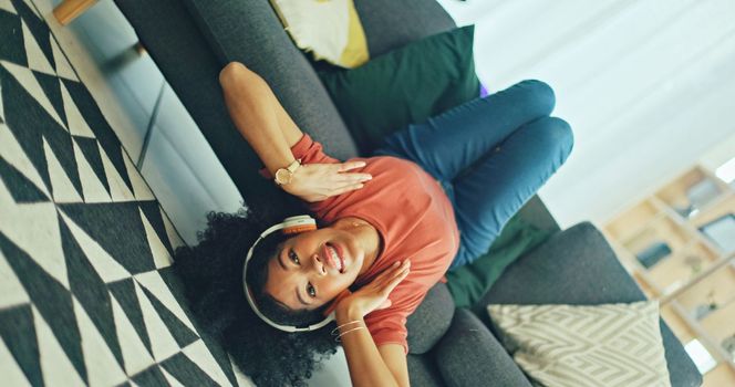 Headphones, listening and dance of black woman on a sofa excited for subscription service, technology and home connection. Happy, relax and girl portrait dancing on couch while listening to music app