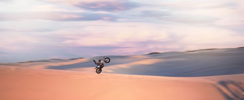 Desert dunes, moto cross and sports adventure athlete doing a extreme jump with speed. Travel, sand and bike with energy of a man athlete cycling on dirt with challenge and sport race with freedom