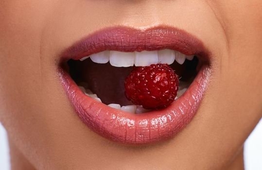 Red lips to match his red flags. an unrecognizable womans perfect teeth biting on a raspberry.