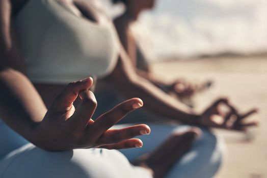 Change begins within. a woman meditating during her yoga routine on the beach.