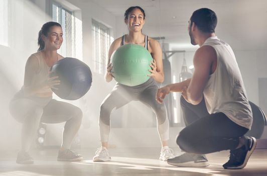 Hes here to help us reach our fitness goals. two women using fitness balls while working out with their trainer.