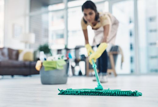 Cleanliness comes first in her home. a young woman mopping the floor at home.