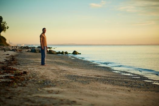 Nature is my home. a man standing at the waters edge of a beach.