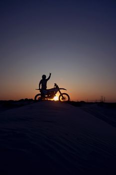 Motorcycle, success and person silhouette celebrating victory against a night, sky and background in nature. Sports, motorbike and biker stop for accomplishment, achievement and biking on dirt road