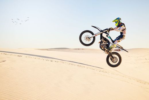 Motorcycle, desert race and air jump for extreme sport expert with agile speed, power or balance in nature. Motorbike man, rally and blue sky on fast vehicle with helmet, safety clothes or motivation