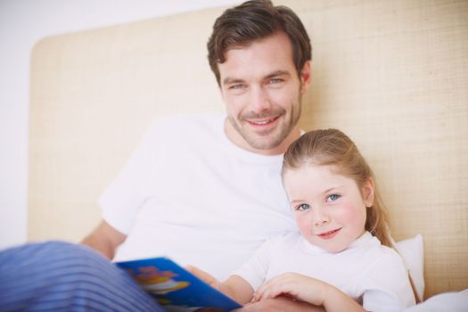 She loves storytime. A devoted father reading his young daughter a bedtime story.