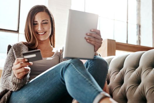 Payment, digital tablet and credit card by woman on a sofa, ecommerce and online shopping in her home. Girl, online shopping and relax checking debit card for purchase or subscription in living room