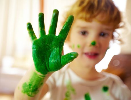 Mom says eco friendly paint is the best. Portrait of a messy child displaying their painted hand.