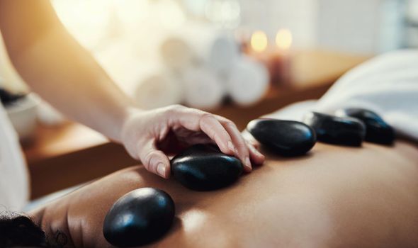 Hot stone massage are a helpful way to ease muscle tension. Closeup shot of a woman getting a hot stone massage at a spa.