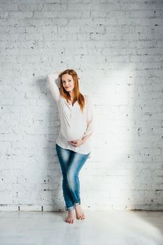 red-haired pregnant girl in a light blouse and blue jeans