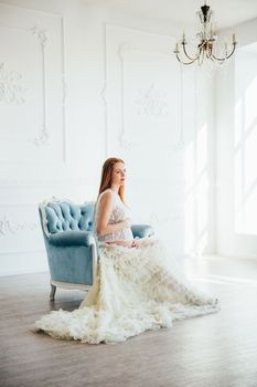 red-haired pregnant young girl in a blue armchair