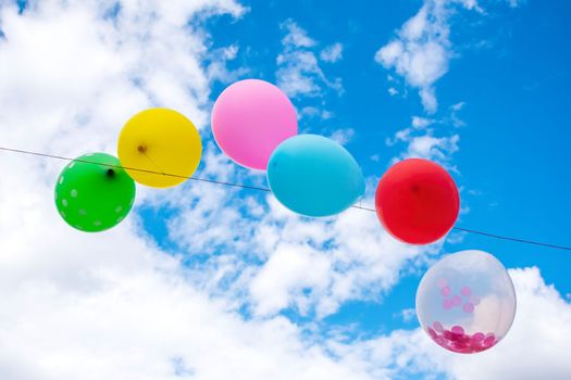 Party balloons in front of a cloudy sky.