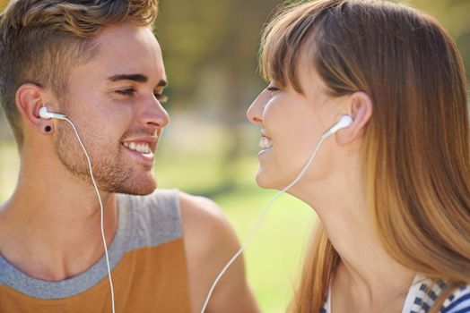 This is our song...A loving young couple sharing a pair of earphones and listening to music.