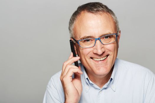 Staying in touch has never been easier. Studio portrait of an older man talking on a mobile phone.