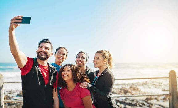 Its more fun exercising with friends. a fitness group taking a selfie while out for a run on the promenade.