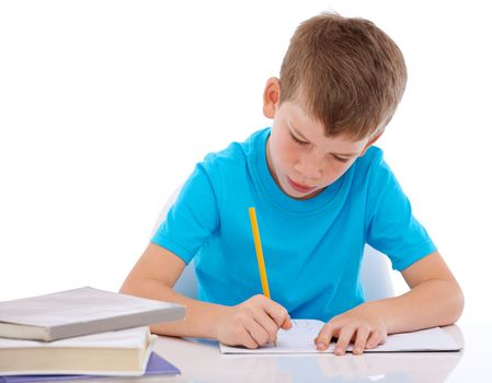 Young boy, writing and learning homework at desk for school, education and student knowledge. Paper, working and child with books for study, creative drawing or academic preschool practice in studio
