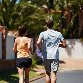Come on, keep up. Rearview shot of an unidentifiable couple jogging together in their neighborhood.