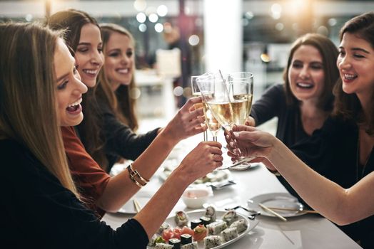 Toasting their friendship. a group of young girlfriends toasting during a dinner party at a restaurant.