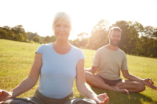 Drop and give me zen. a happy mature couple doing yoga together outdoors.