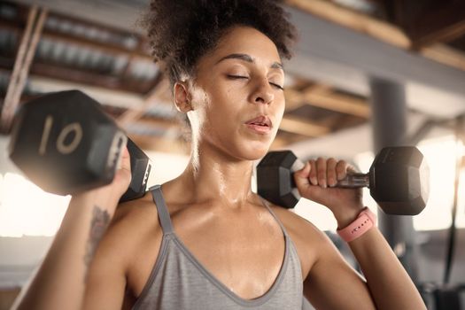 Fitness, exercise and dumbbell with a black woman athlete training in a gym for strong health or wellness. Sports, motivation and workout with a female bodybuilder in a sports club for a workout