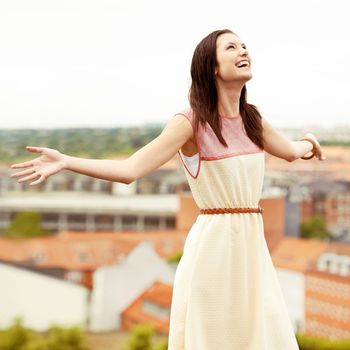 Loving every moment. Gorgeous young woman standing on a rooftop with her arms outstretched.