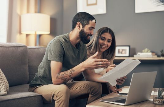 With regular saving, financial wellness is on its way. a young couple using a laptop while going through paperwork at home.