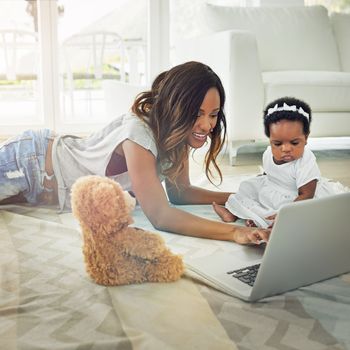 Growing up with technology. a mother using a laptop with and her baby daughter at home