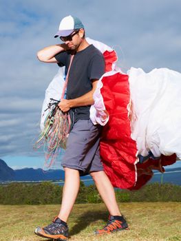 Ready to rock the skies. a man carrying his paragliding equipment.
