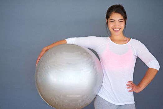 Exercise is my natural high. a sporty young woman holding a pilates ball against a grey background.