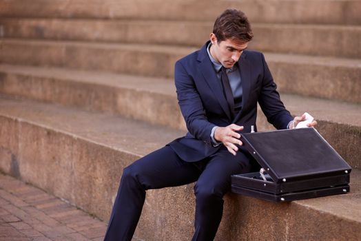 Ready to win his case. a businessman looking into his briefcase while sitting on some steps.