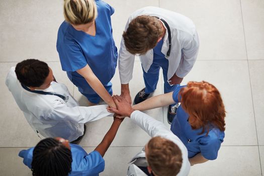 Theyre a team devoted to delivering quality healthcare. High angle shot of a group of medical practitioners joining their hands together in unity.