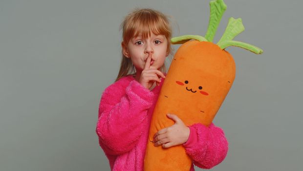 Preteen child girl presses finger to lips makes silence hush sign do not tells gossip secret, quiet