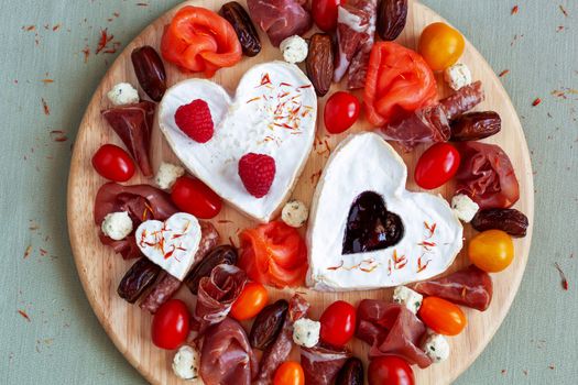 Cheeseplate with heart shape cheese, fruits and delicatessen