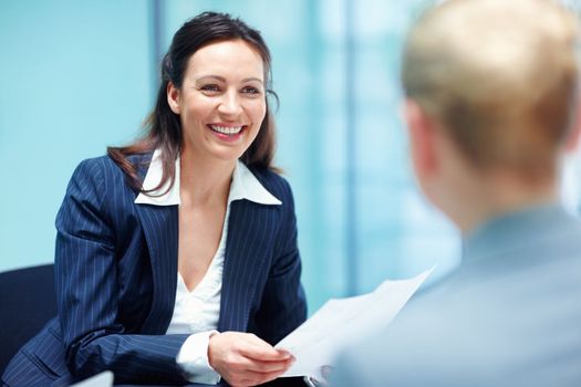 Smiling business woman conversing with executive. Portrait of lovely business woman smiling while conversing with executive in office.