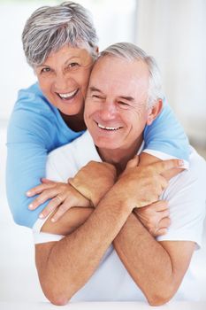 Cheerful mature couple embracing at home. Portrait of cheerful mature couple embracing while relaxing at home.