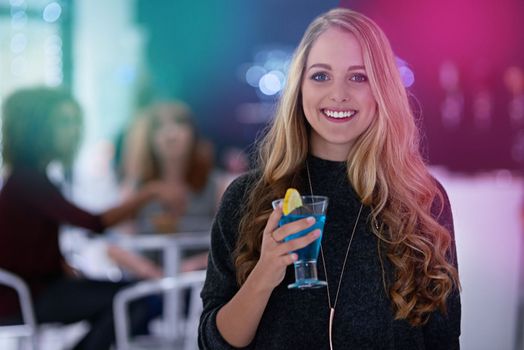 Friday night is ladies night. Portrait of a happy young woman enjoying a cocktail in a nightclub.