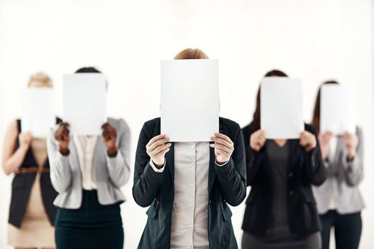 They each have something to say. a group of unrecognizable businesspeople holding blank pieces of paper over their faces against a white background.