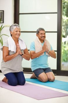 Peaceful and focused. Portrait of a mature couple doing yoga together at home