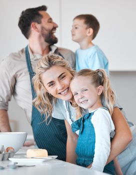 Mother and father baking with their children. Siblings baking with their parents in the kitchen. Portrait of a mother bonding with her daughter. Happy woman hugging her child. Family baking together.