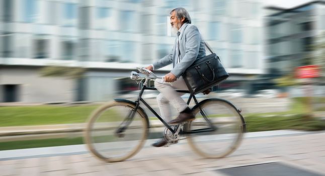 Bike, commute and blurred motion with a mature man in business cycling in the city on his morning trip into work. Road, travel and bicycle with a senior male employee riding on a street in town