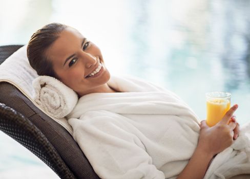 Calm waters, calm mind. a young woman drinking a glass of orange juice at the day spa.