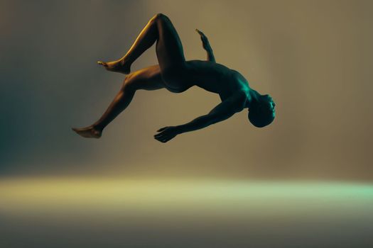 Shadow, black man and nude model in a studio background for creative art with lights. Isolated, floating and young naked body of a african person in the air with light showing dark art deco glow