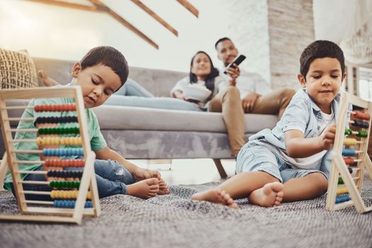 Math, family or children learning for development growth with mother and father relaxing watching tv. Education, siblings or young boys playing fun toys or counting games for kids at home together